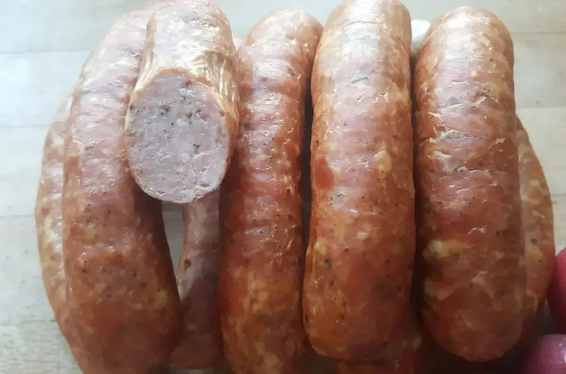 Kilka grubych, wędzonych kiełbas, jedna przekrojona, ukazująca mięsiste wnętrze. Idealne do grillowania, zastanawiasz się, ile parzyć kiełbasę wędzoną?