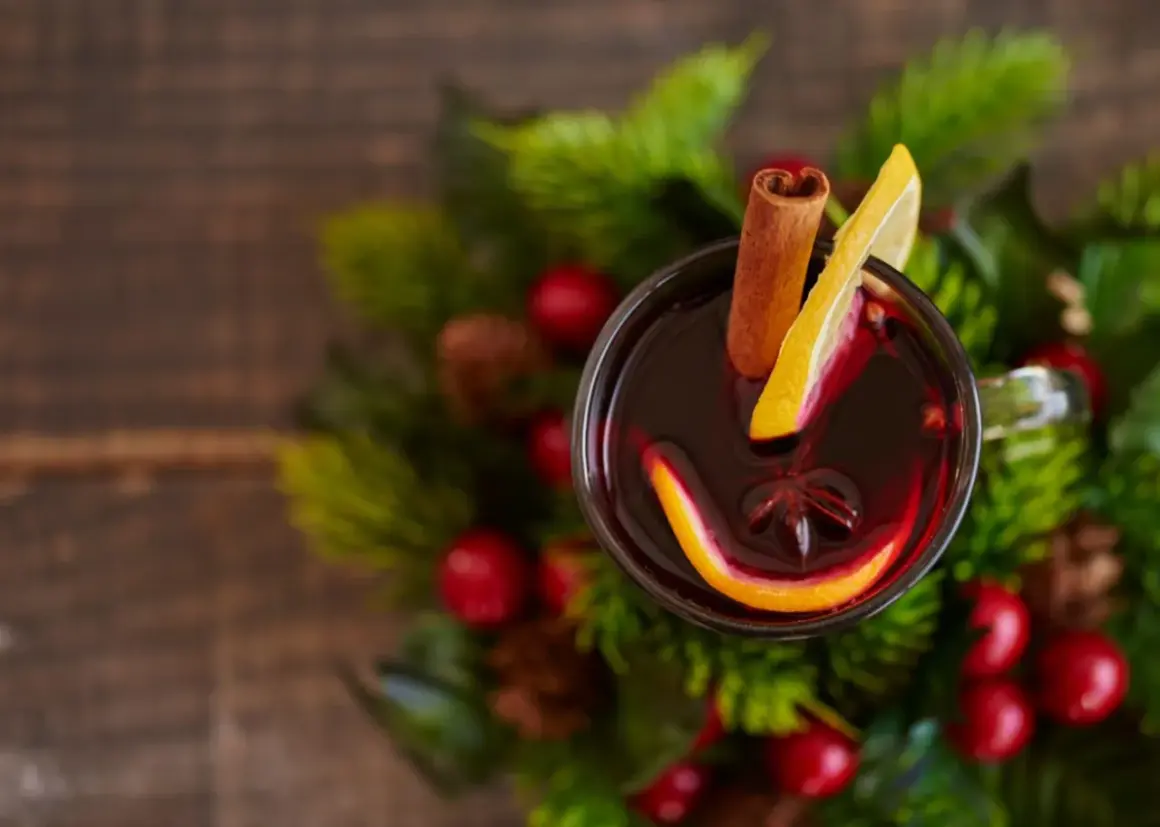 Glogg przepis: aromatyczny grzaniec z pomarańczą, cytryną i cynamonem, otoczony świątecznymi gałązkami.