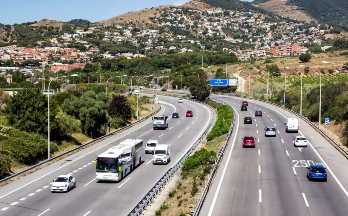 Voiture sur autoroute en Espagne, respectant la limitation vitesse espagne. Paysage vallonné avec des maisons en arrière-plan.