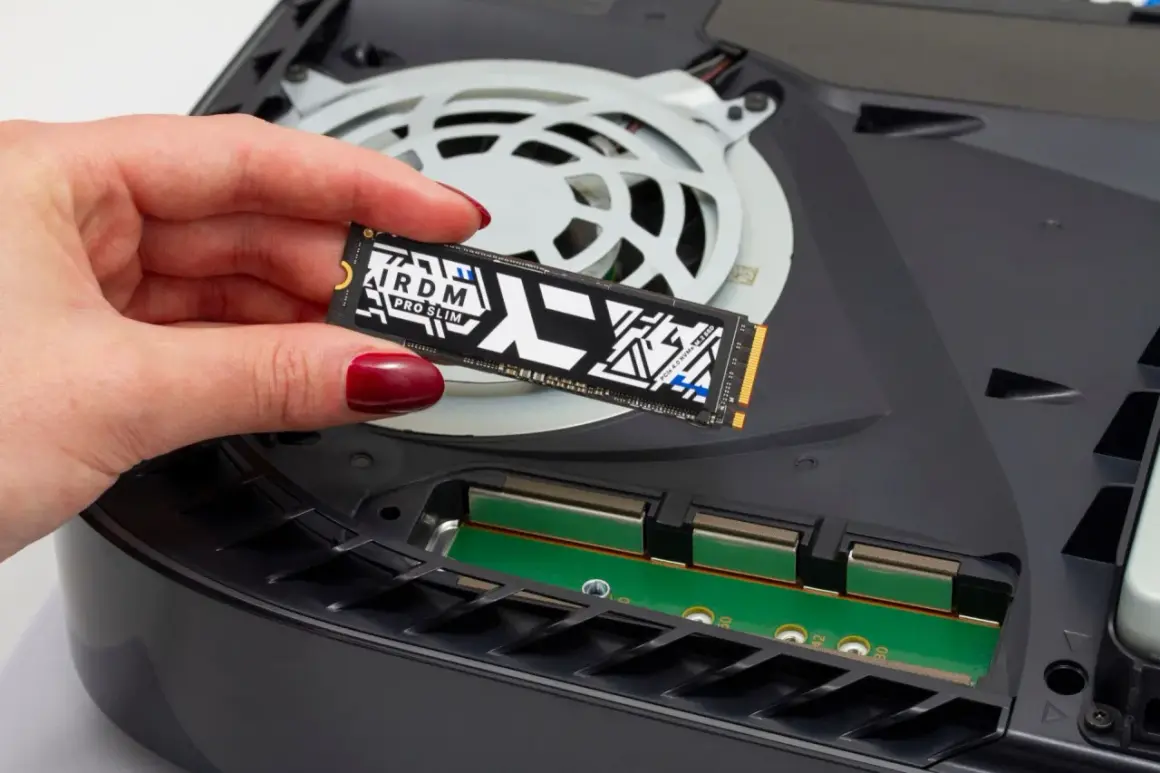 Dłoń z czerwonym lakierem trzyma dysk SSD M.2 PCIe 4.0 NVMe, gotowy do montażu w konsoli.