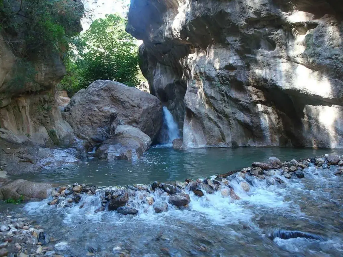 Un rincón idílico en las cascadas de Padules, Almería, donde el agua cristalina fluye entre rocas y vegetación exuberante.
