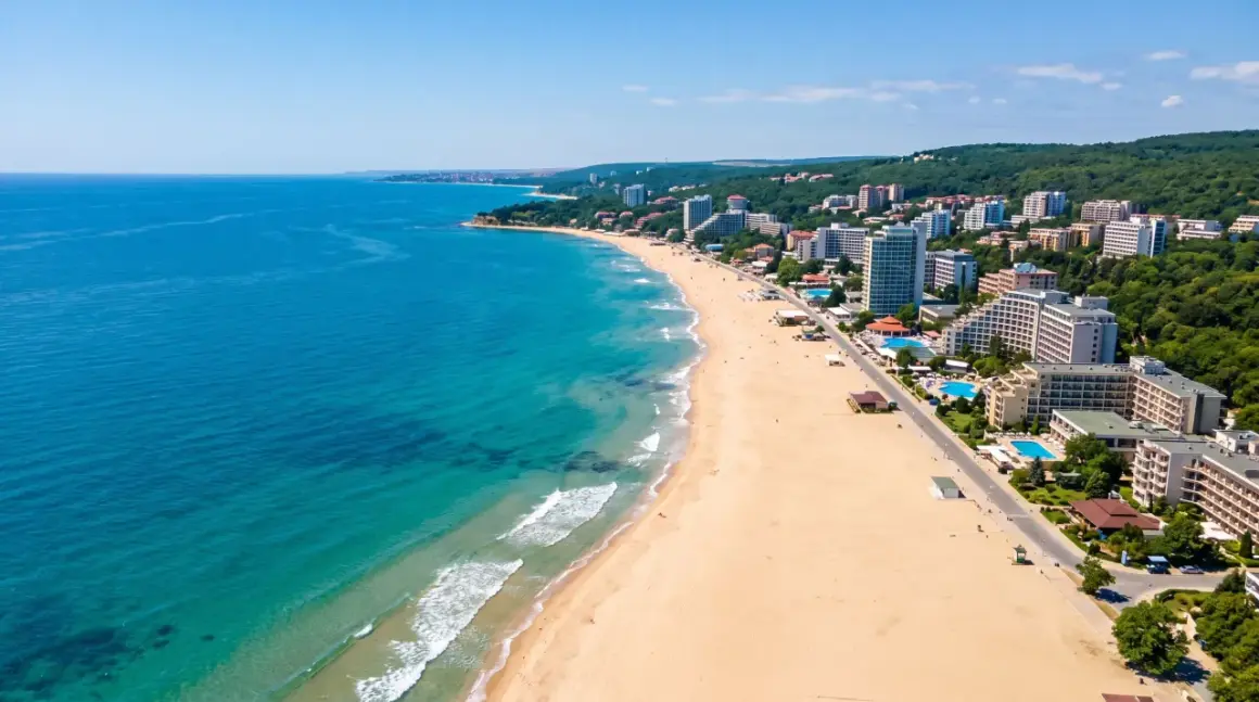 Bułgaria, czerwiec: słoneczna pogoda na szerokiej plaży z hotelami i turkusowym morzem. Idealne warunki na wakacje.