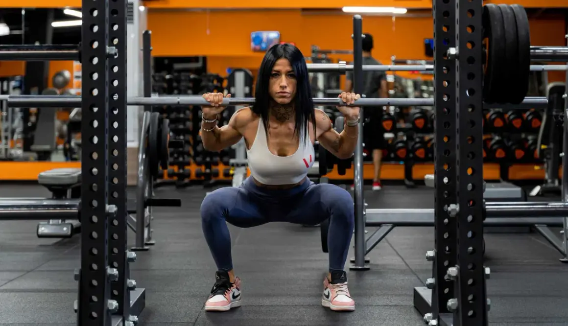 Donna determinata esegue uno squat a casa con bilanciere, concentrata sul suo allenamento.