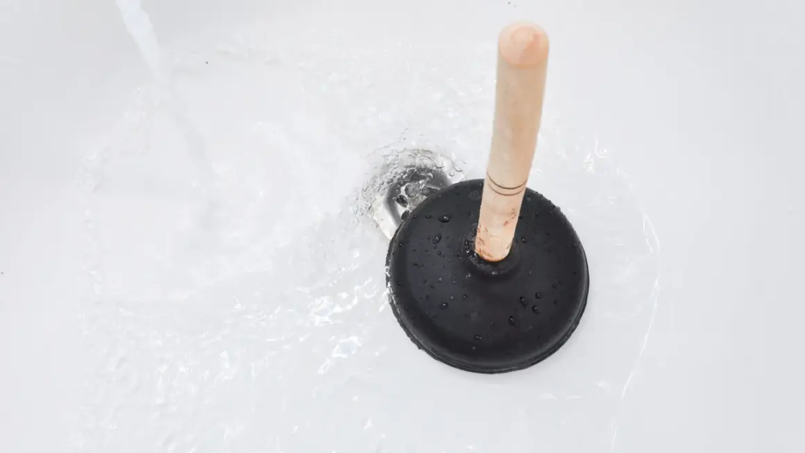 Ventouse sur un drain de baignoire avec de l'eau qui coule. Une solution simple pour savoir comment déboucher une baignoire rapidement.