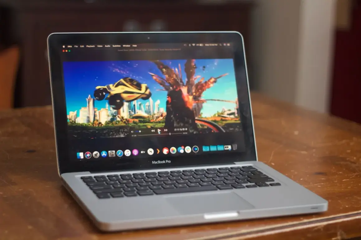 A MacBook Pro displays the "Speed Racer" trailer on the IINA player, showing a futuristic city and a car mid-explosion.