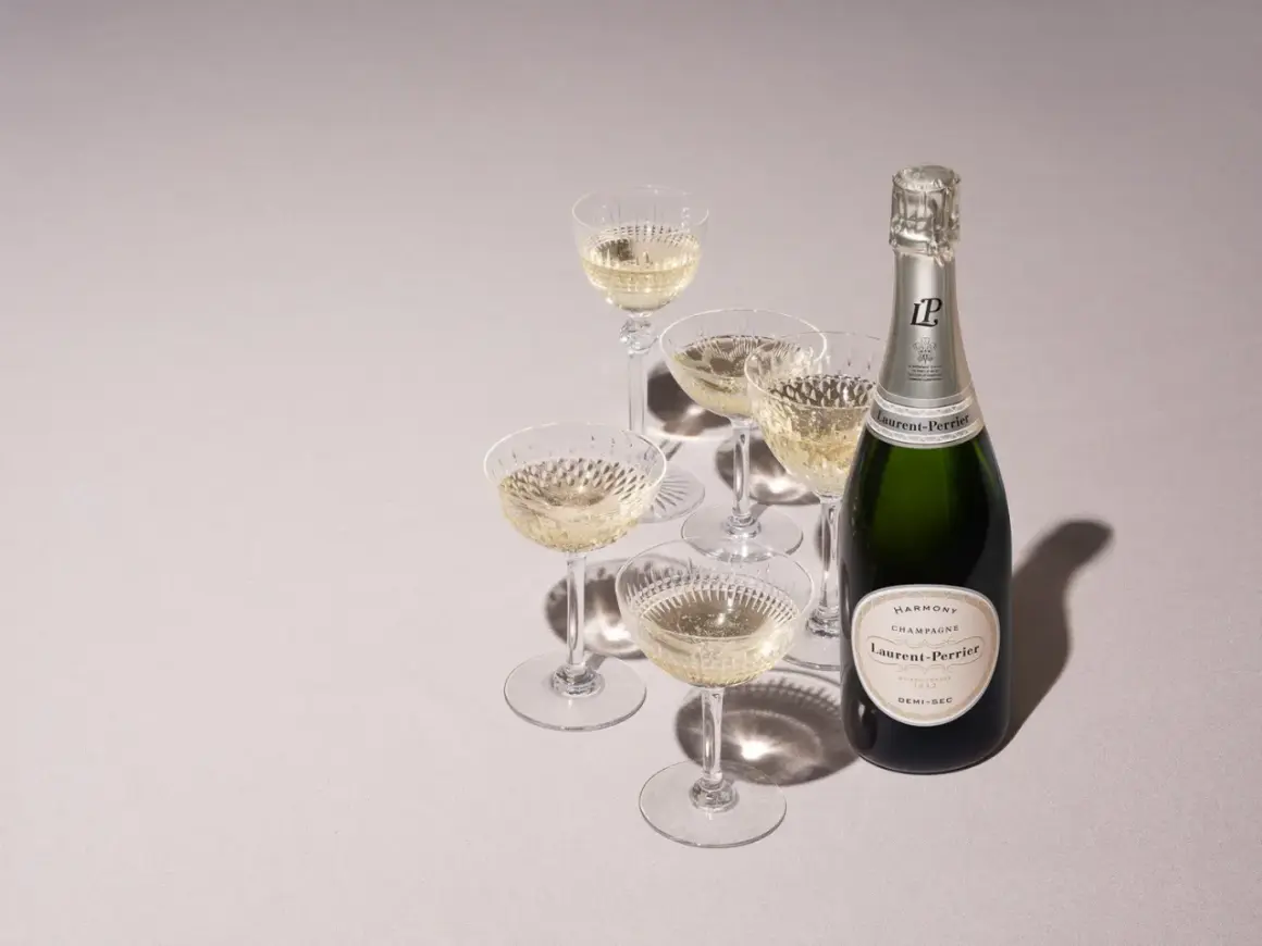 Laurent-Perrier Champagnerflasche mit gefüllten Gläsern. Die Dosage Champagner Bedeutung liegt in der perfekten Balance.