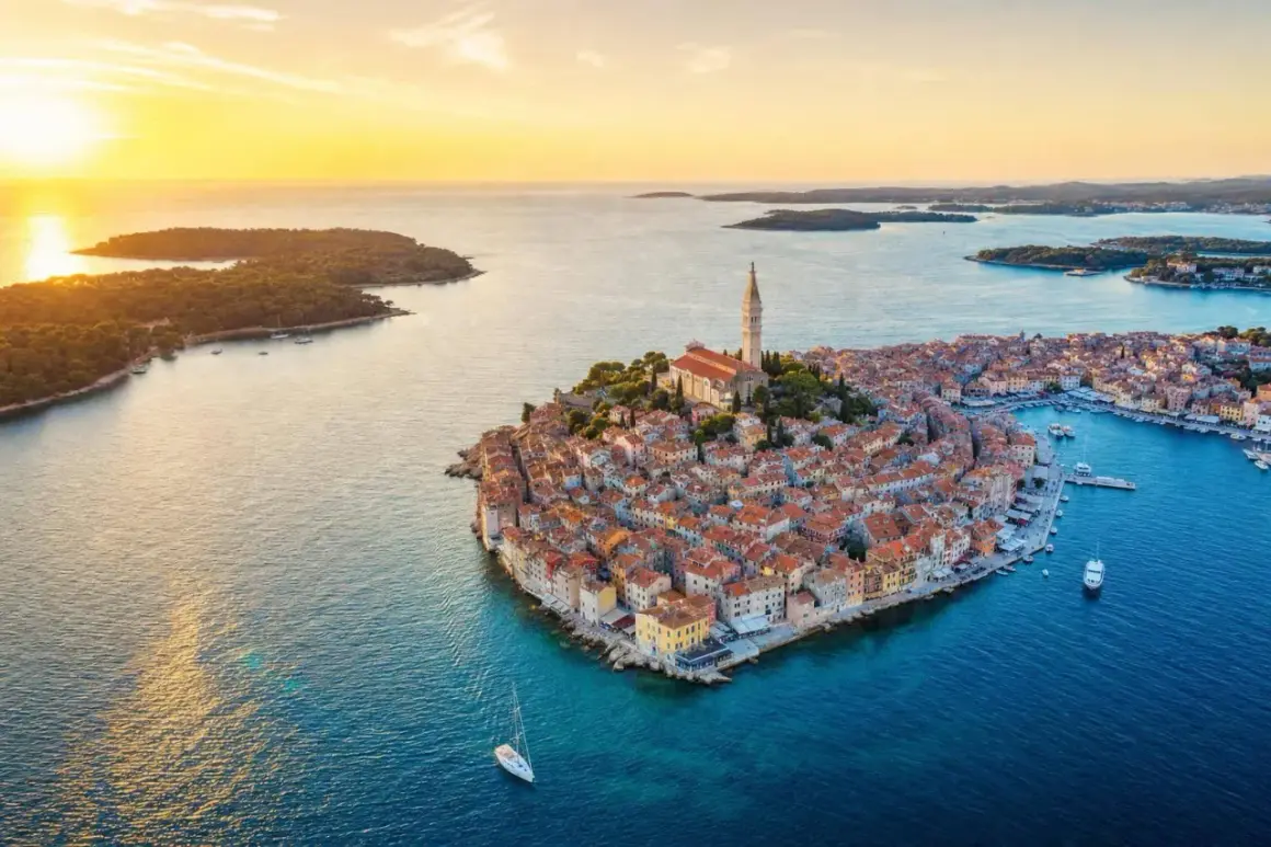Malownicze miasteczko Rovinj w Chorwacji o zachodzie słońca. Dachy domów i kościół św. Eufemii lśnią w złotym świetle.