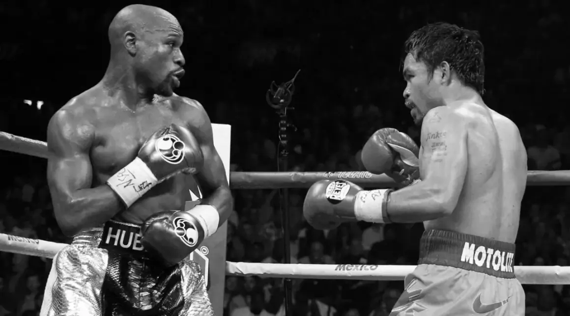 Floyd Mayweather Jr. in his signature defensive stance, facing Manny Pacquiao in a boxing ring.