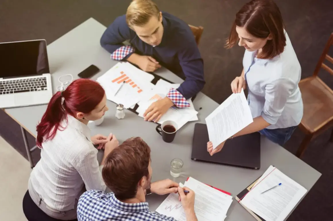Vier Personen besprechen Dokumente und Diagramme. Sie zeigen **soziale Intelligenz** im Austausch von Ideen und im gemeinsamen Arbeiten.