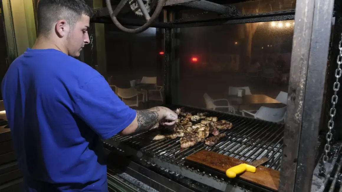 Joven cocinero prepara carnes a la parrilla en un restaurante, quizás en los charros cabo de gata.