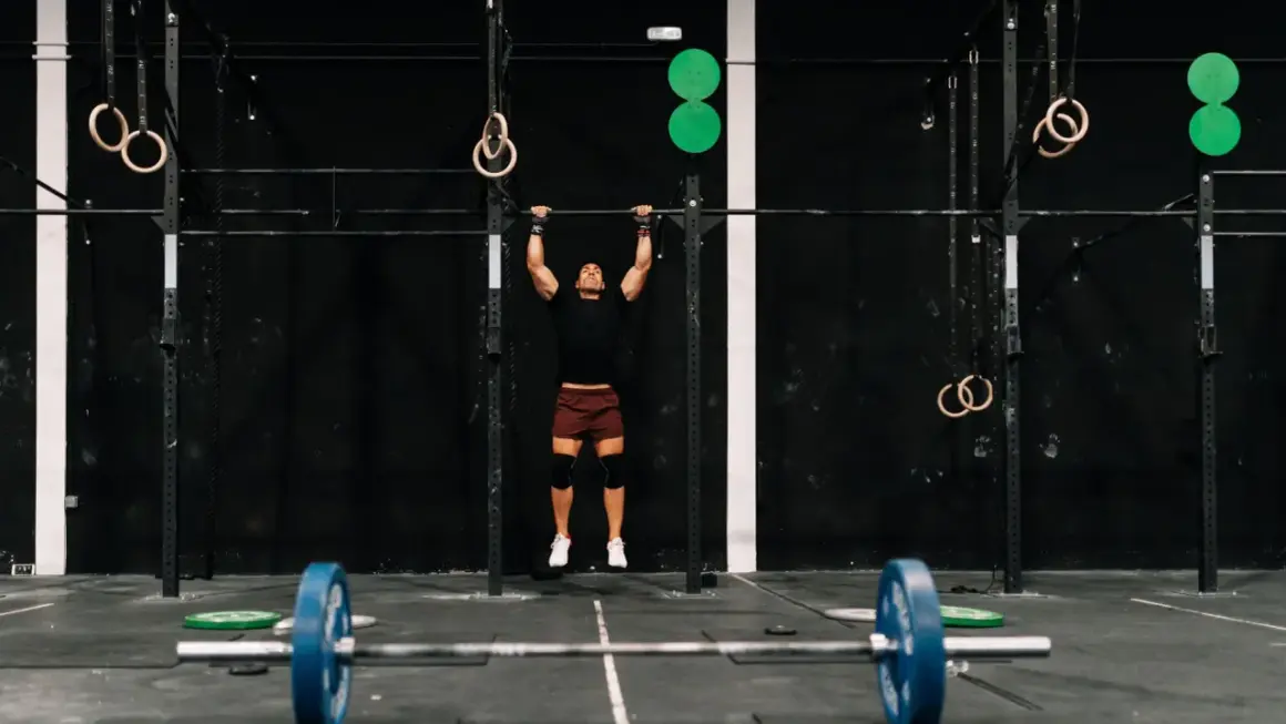 Mężczyzna wykonujący podciąganie na drążku w siłowni CrossFit.