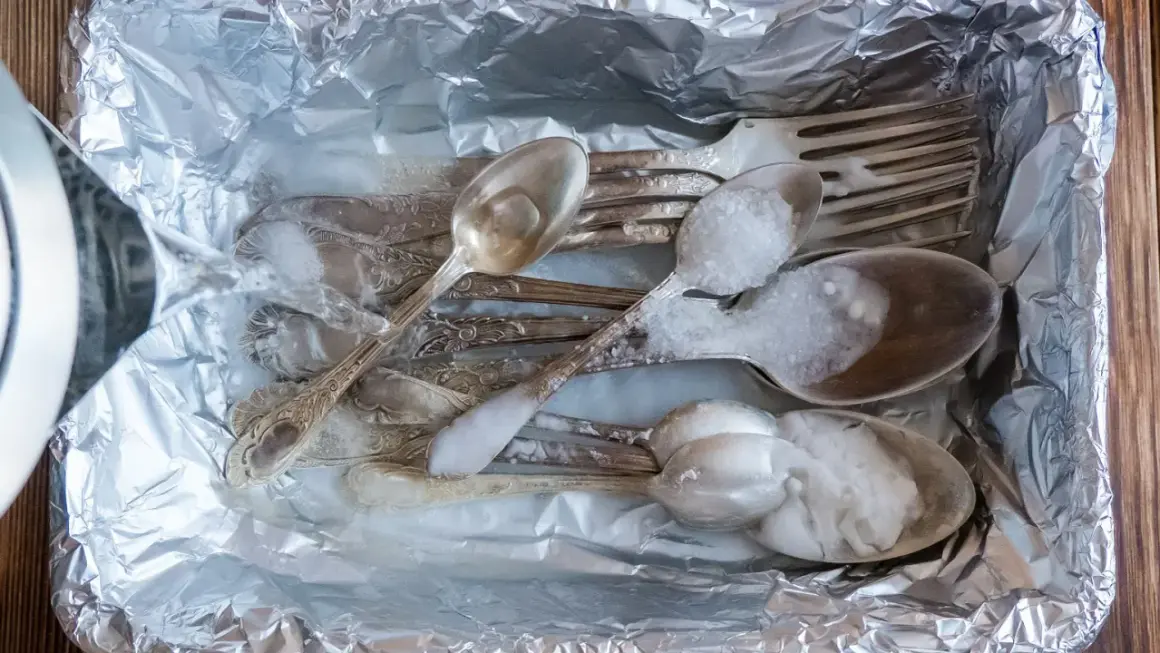 Srebrne sztućce w folii aluminiowej, zalewane wrzątkiem z solą. Prosty sposób, jak wyczyścić srebro w domu.