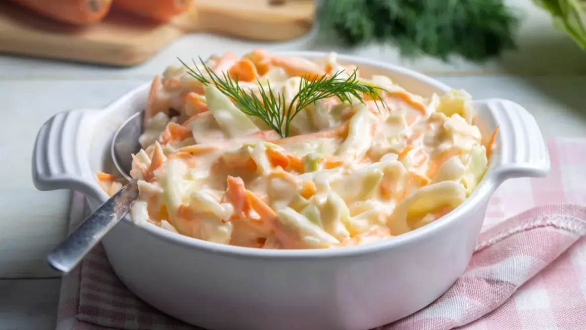 Deliciosa ensalada americana cremosa, con repollo y zanahoria rallados, adornada con eneldo fresco.