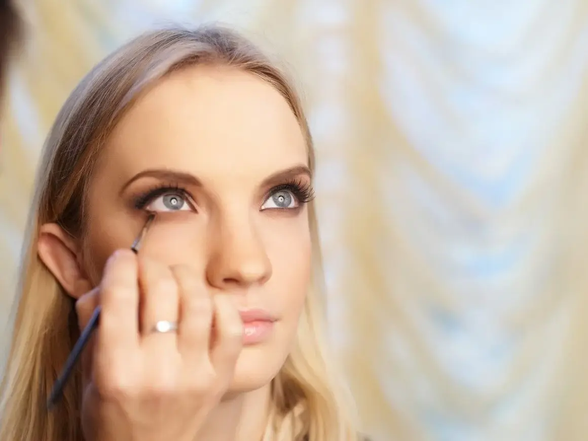 Kobieta z blond włosami otrzymuje makijaż oczu, który przypomina styl makijaż lata 20.