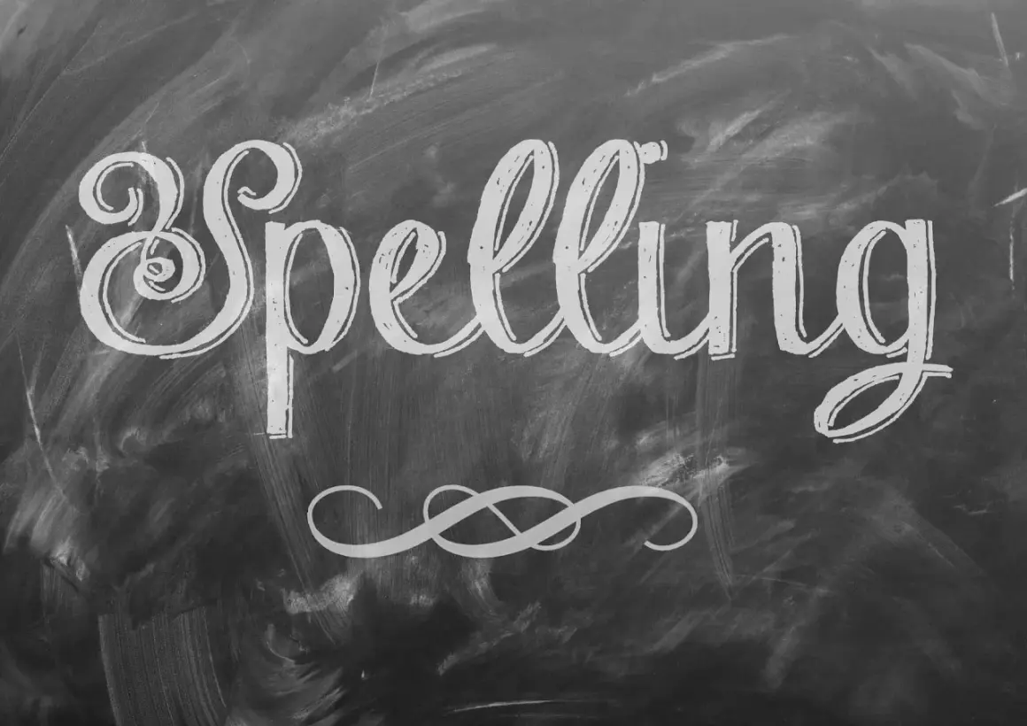 Het woord "Spelling" is met sierlijke letters op een krijtbord geschreven. Een decoratieve krul siert de onderkant.