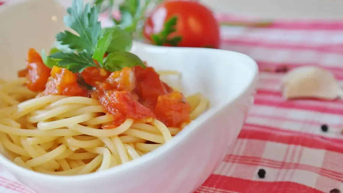 Eine Schüssel mit Spaghetti und einer herzhaften Tomatensoße, garniert mit frischem Basilikum und Petersilie.