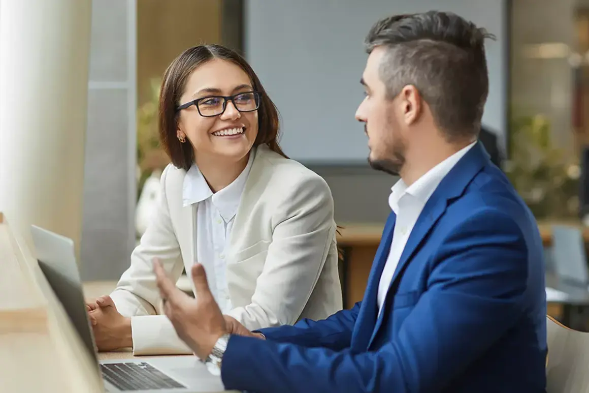 Ein Mann und eine Frau besprechen am Laptop die Gehaltsentwicklung einer Finanzwirtin.
