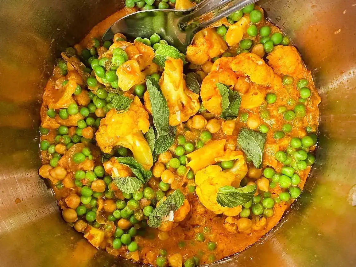 En smakrik vegetarisk gryta med blomkål, kikärtor och gröna ärtor, toppad med färsk mynta.