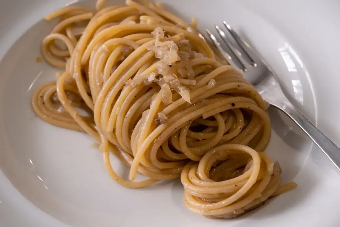 Un piatto di bigoli con le sarde, pasta fresca condita con un sugo saporito.