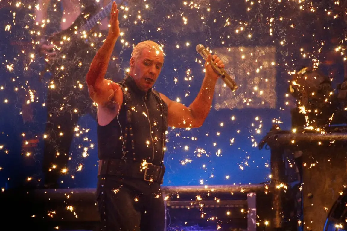 Till Lindemann z Rammstein śpiewa na koncercie, otoczony fajerwerkami.