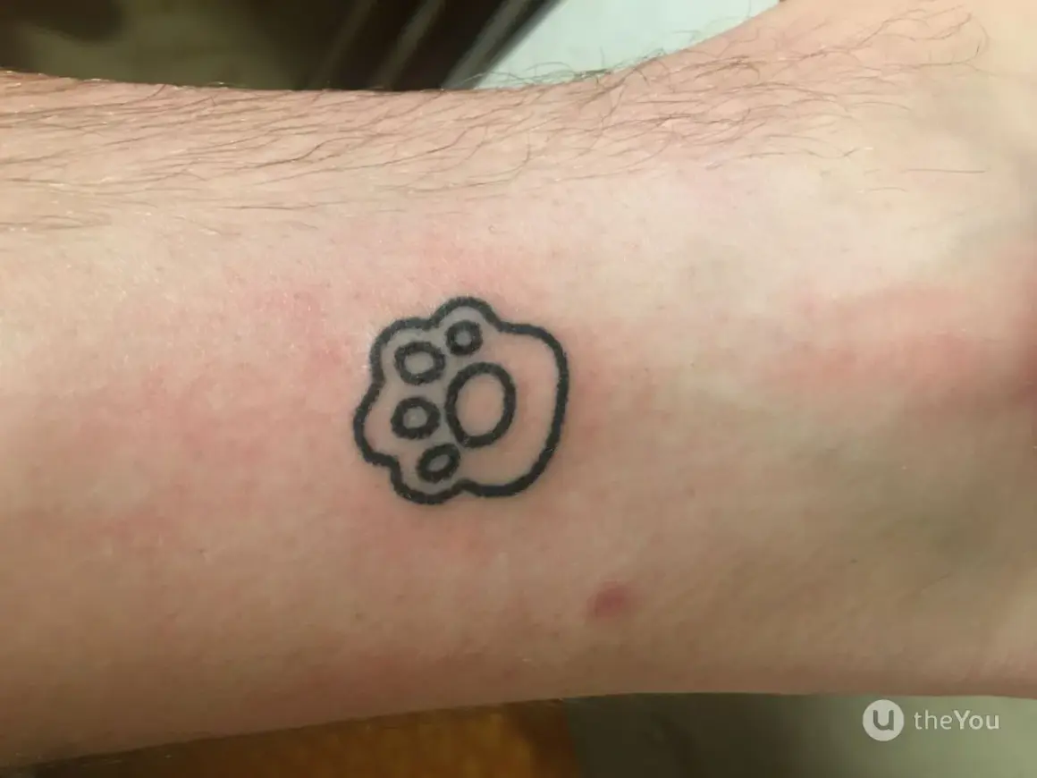 Małe tatuaże męskie: czarna łapka zwierzęcia na skórze, symbol przyjaźni i lojalności.