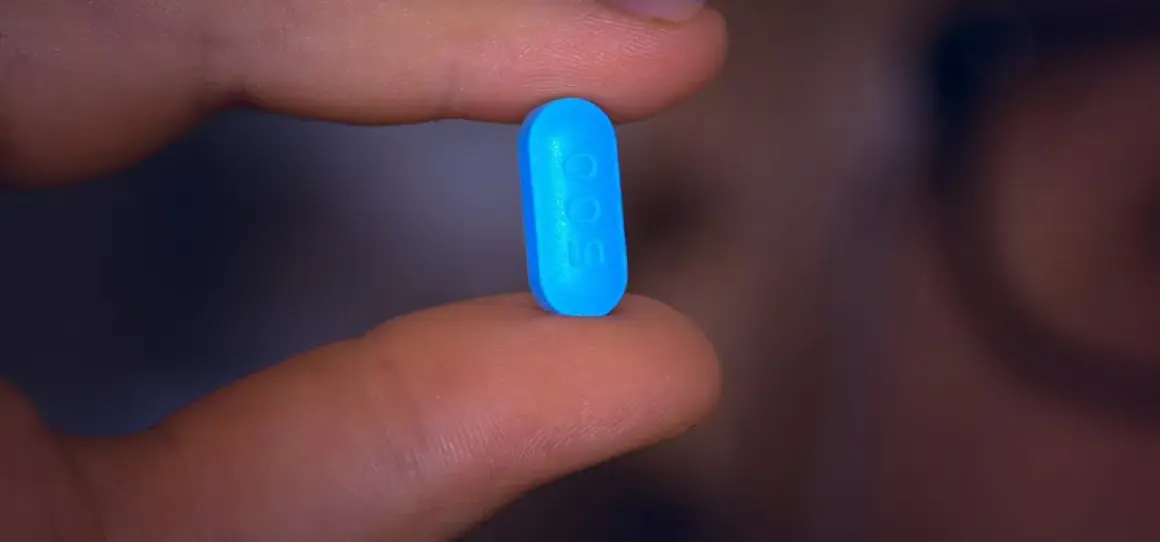 En blå tablett med siffran 500 hålls mellan fingrarna, en påminnelse om att motverka diarré vid penicillin.