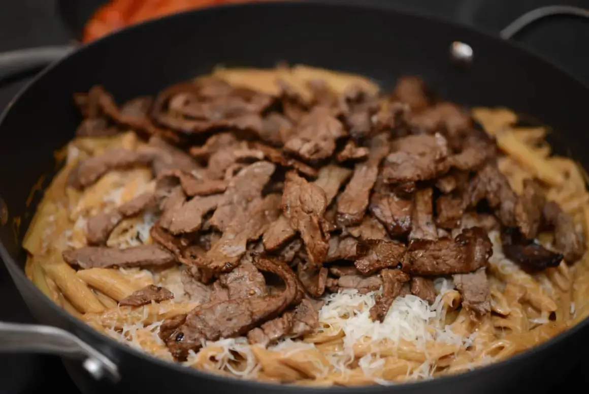 En krämig pasta i ugn med strimlat kött och riven ost.