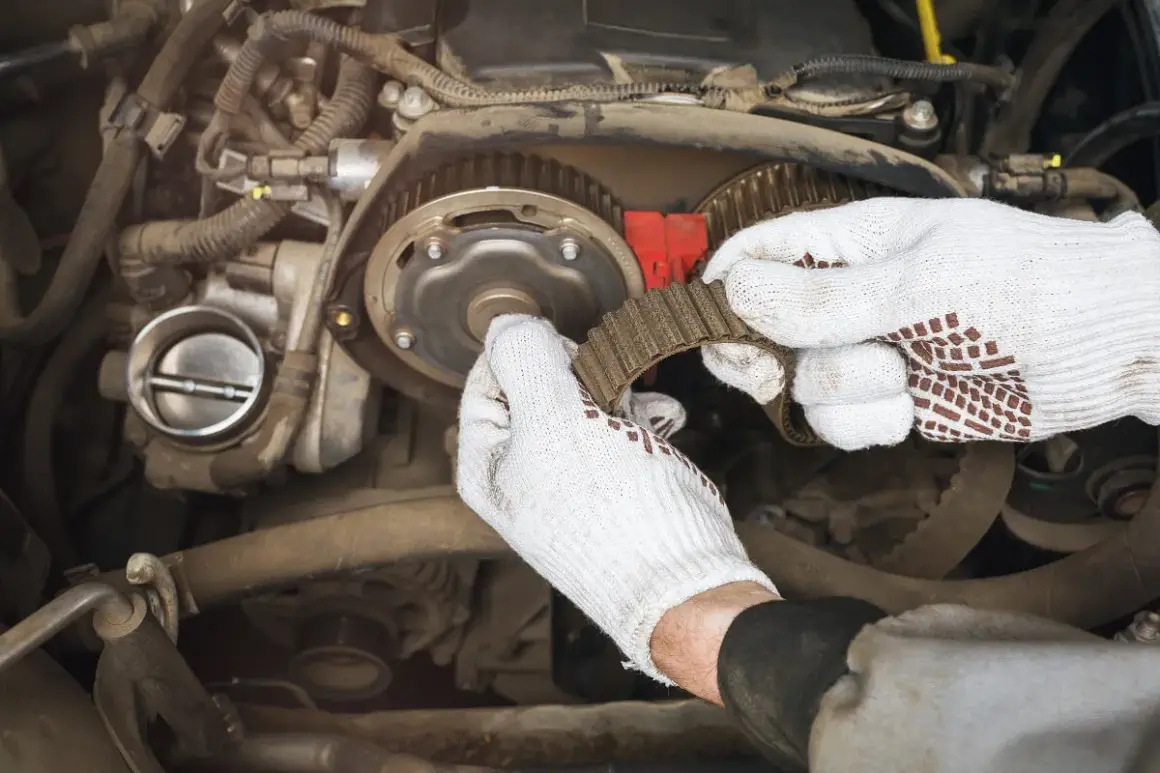 Mechanik w białych rękawiczkach wymienia pasek rozrządu. Czas pracy: ile trwa wymiana rozrządu?