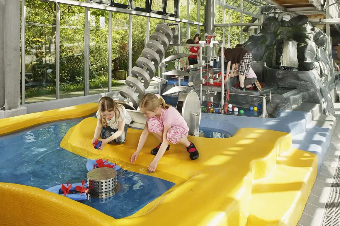 Kinder spielen im Wasserbereich des vier Jahreszeiten Parks Oelde mit bunten Bällen und Wasserrädern.