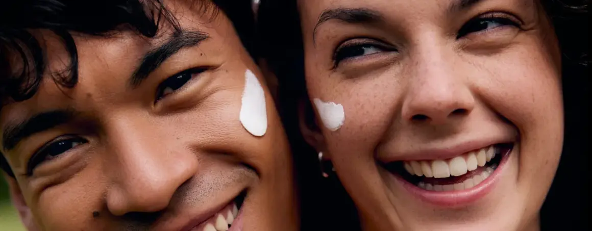 Coppia sorridente con crema sul viso, godendo dei benefici del vapore viso per una pelle radiosa.