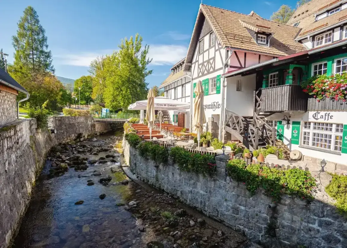 Urokliwy deptak w Szklarskiej Porębie nad górskim potokiem. Restauracja z ogródkiem i zielonymi okiennicami.
