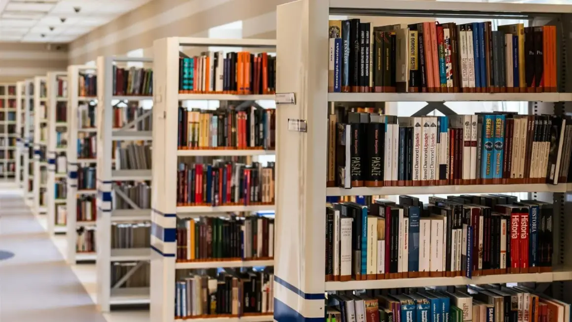 Rzędy regałów z książkami w bibliotece. Wśród nich można znaleźć pozycje dotyczące historii, w tym język chorwacki.