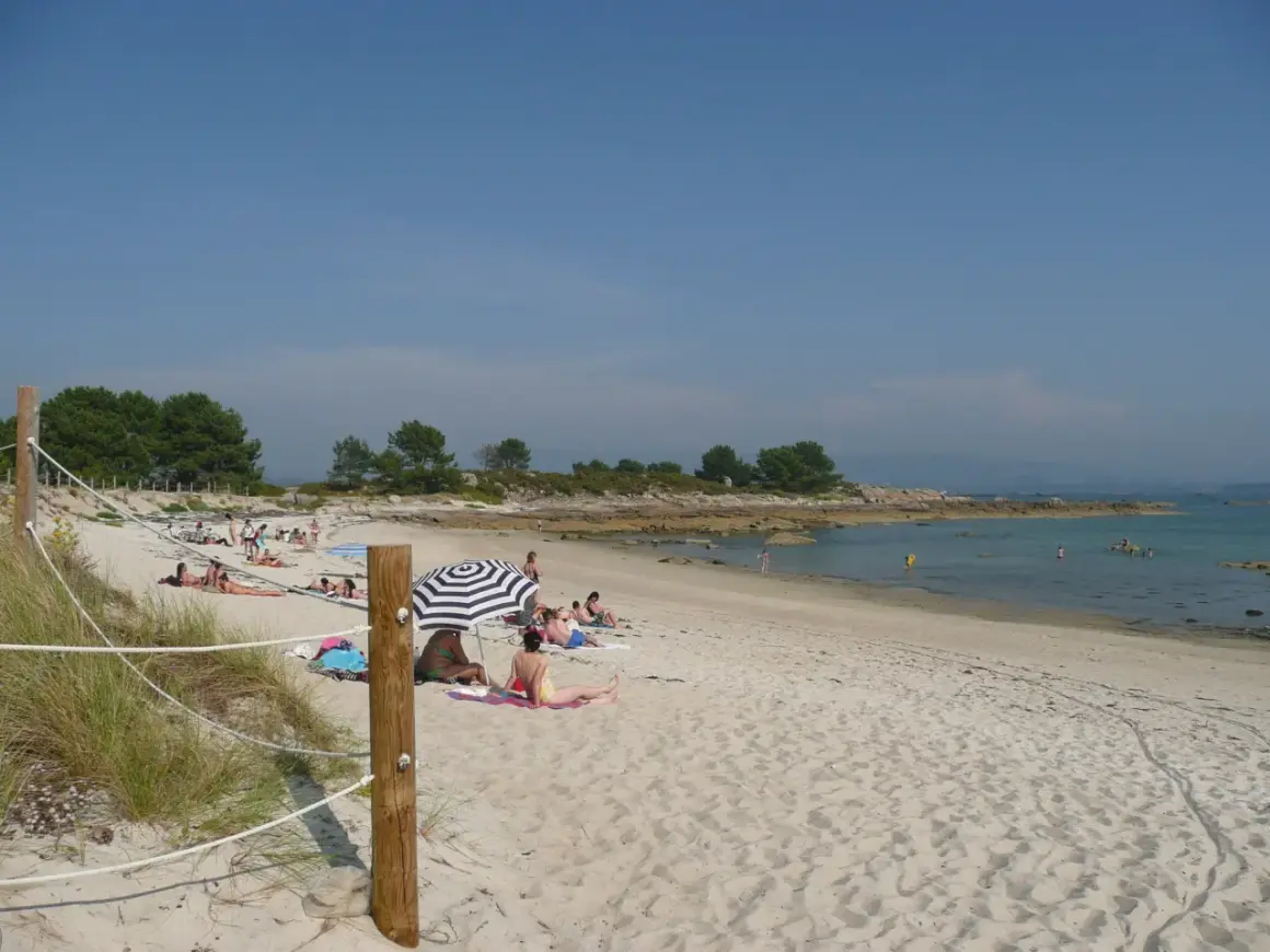 Gente disfrutando del sol en unas tranquilas playas nudistas Galicia, con arena dorada y aguas cristalinas.