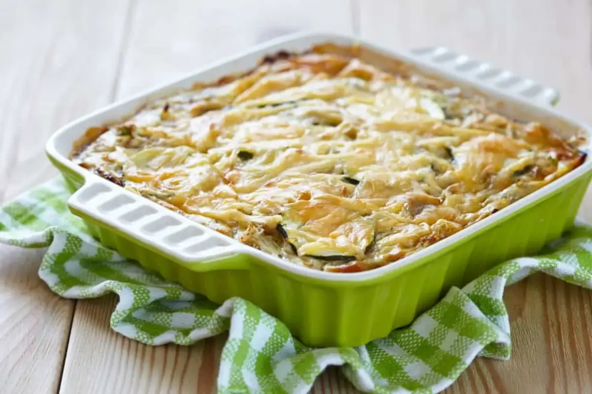 Pastel de calabacín horneado, con queso gratinado y rodajas de calabacín visibles, servido en un recipiente verde sobre un mantel a cuadros.