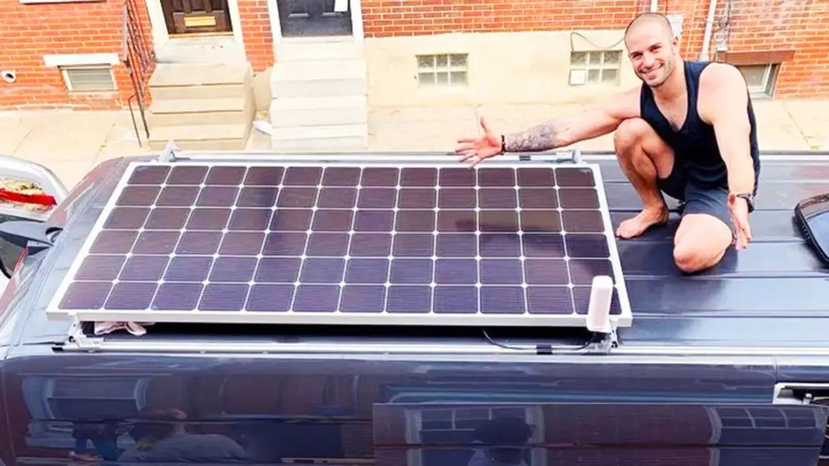 Hombre muestra cómo conectar dos placas solares en el techo de una furgoneta.
