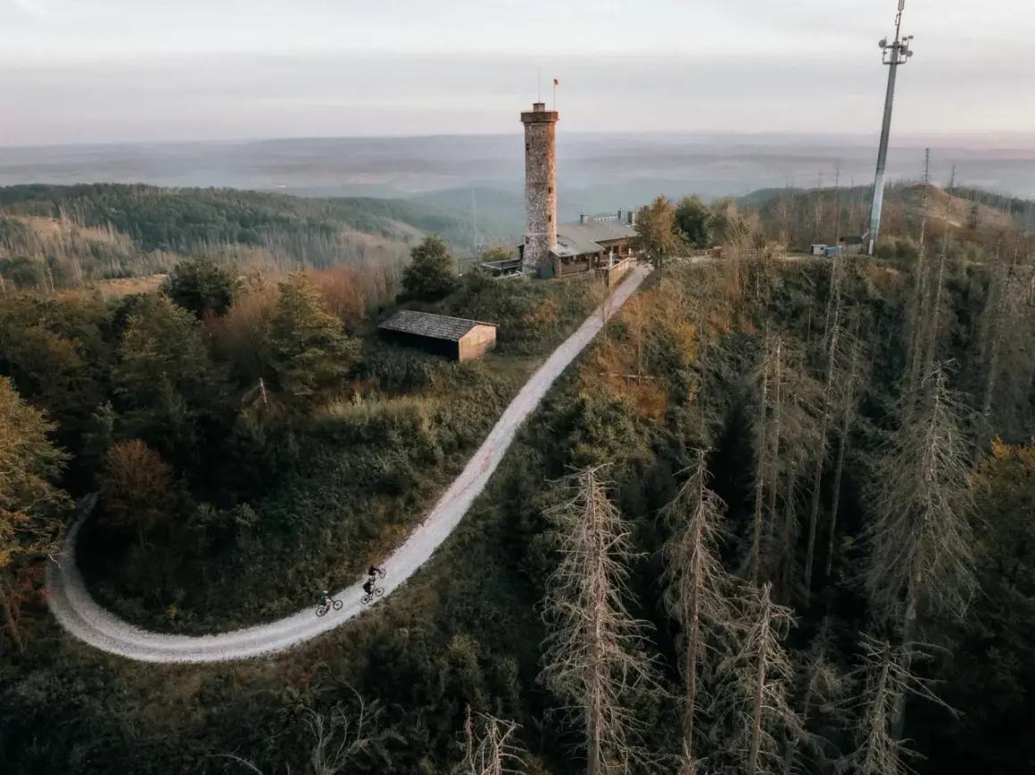 Radfahrer auf einem Weg zum Aussichtsturm Bergneustadt. Der Turm thront über einer bewaldeten Hügellandschaft.