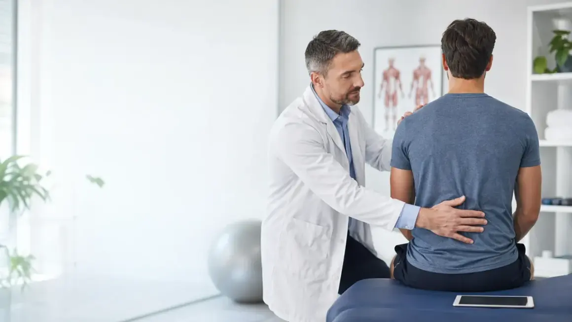Medico esamina la schiena di un paziente, illustrando la differenza tra fisiatra e ortopedico.