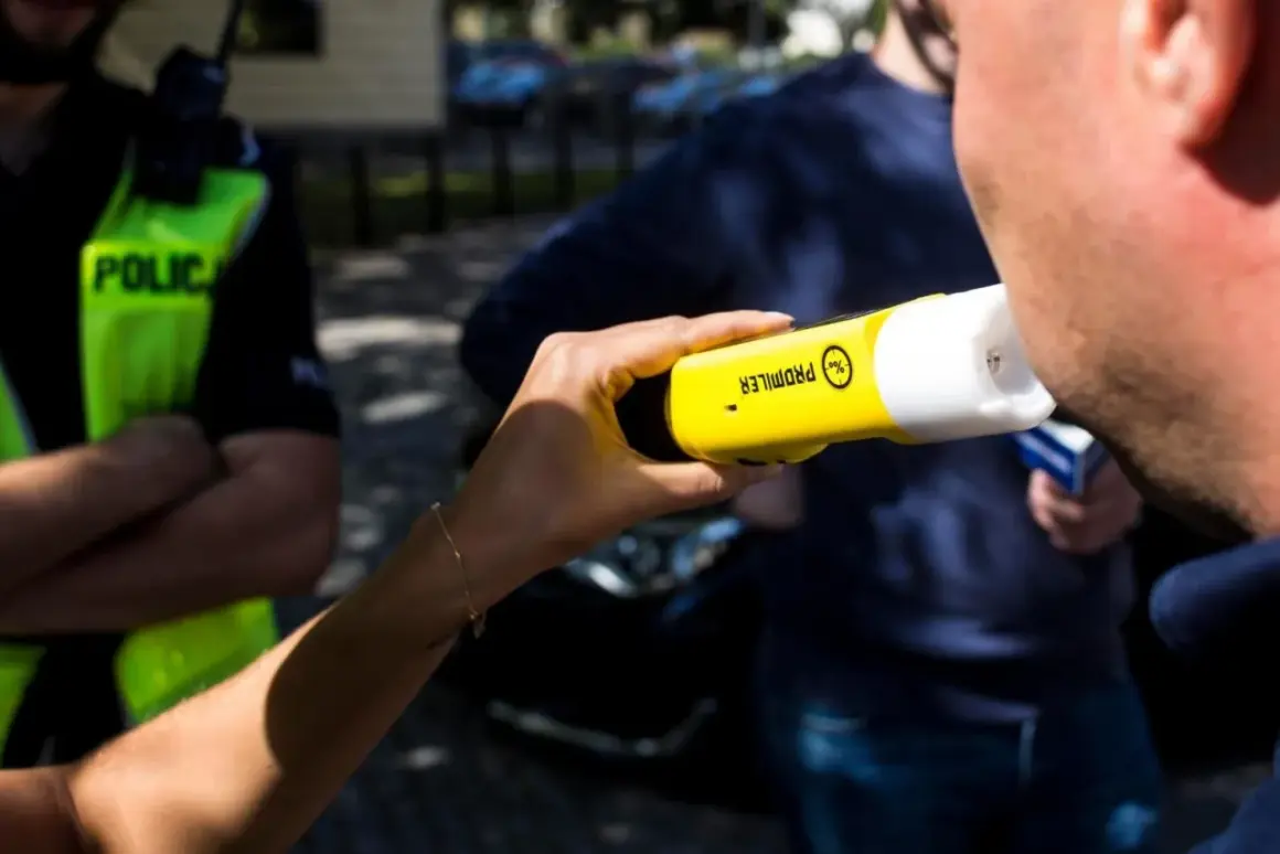 Policjant bada pracownika alkomatem.