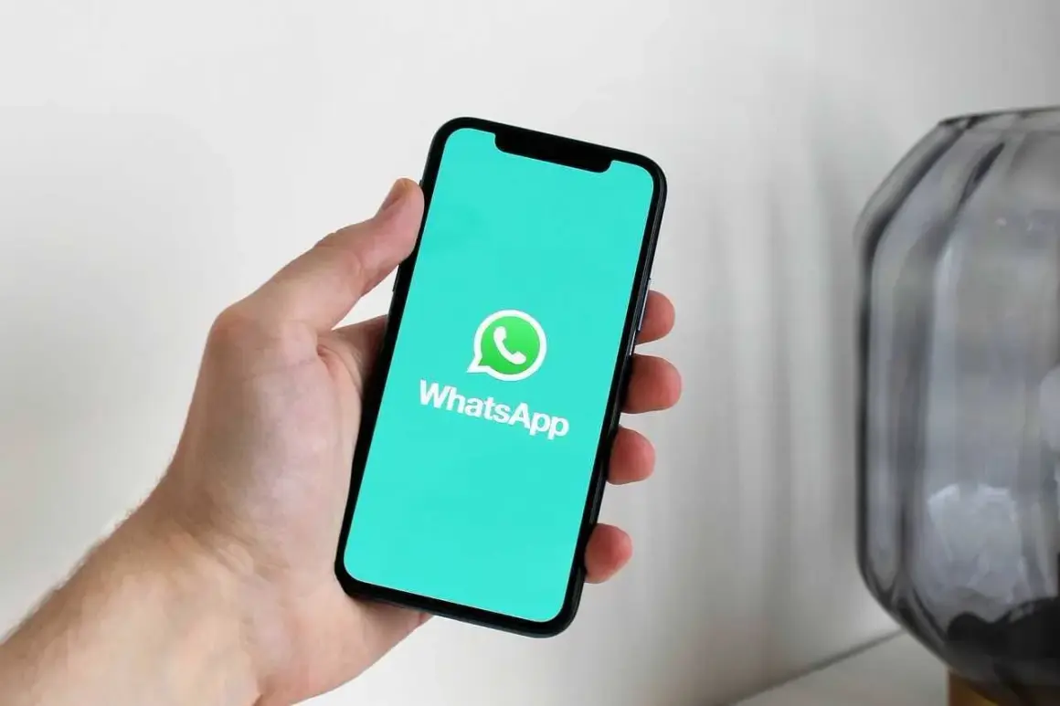 Dłoń trzyma smartfon z logo WhatsApp. Dowiedz się, jak usunąć grupę na WhatsApp, aby uporządkować swoje czaty.