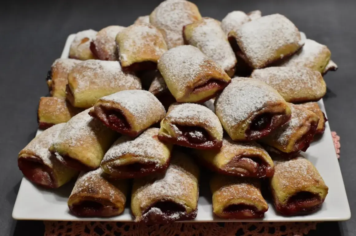 Stos ciasteczek z wiśniami, posypanych cukrem pudrem, wygląda apetycznie.