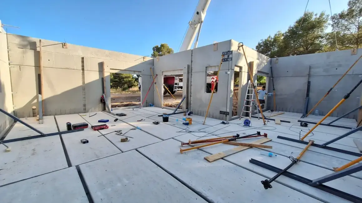 Construcción de una casa prefabricada en Madrid. Se ven paneles de hormigón, puntales y herramientas.