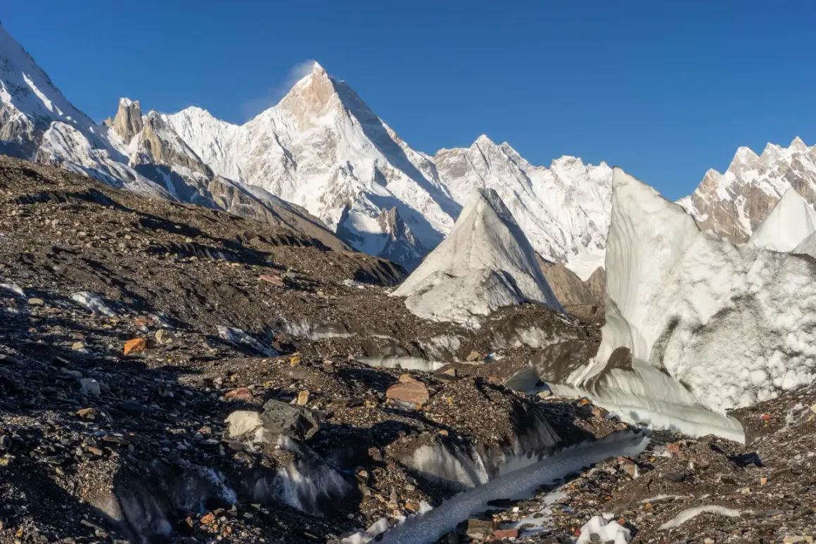 Lodowy krajobraz Karakorum z lodowcem pokrytym kamieniami i lodowymi formacjami. W tle majestatyczne, ośnieżone szczyty.