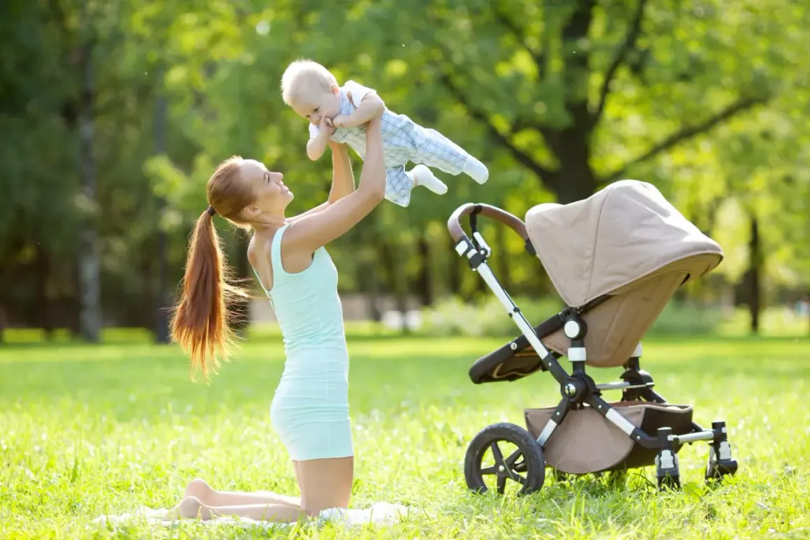 Mama podrzuca noworodka w wózku na trawie w parku.