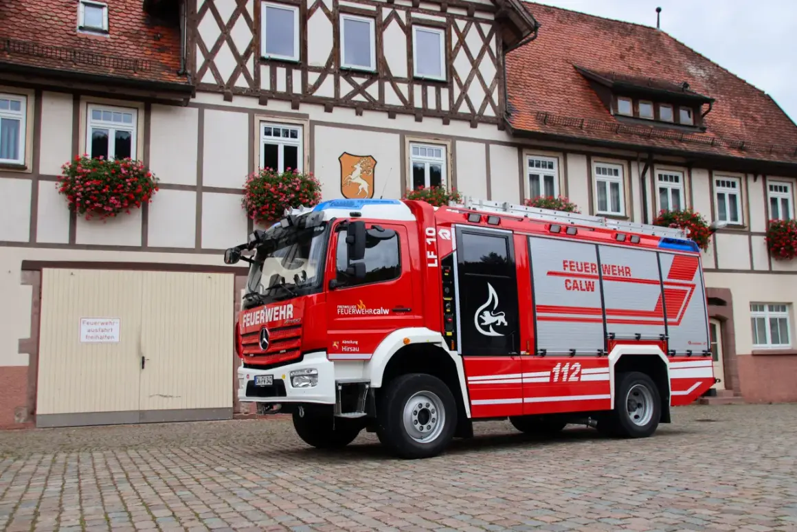 Rotes Löschfahrzeug LF 10 der Feuerwehr Calw, Abteilung Hirsau, vor einem Fachwerkhaus. Das Fahrzeug entspricht der DIN 14530-5.