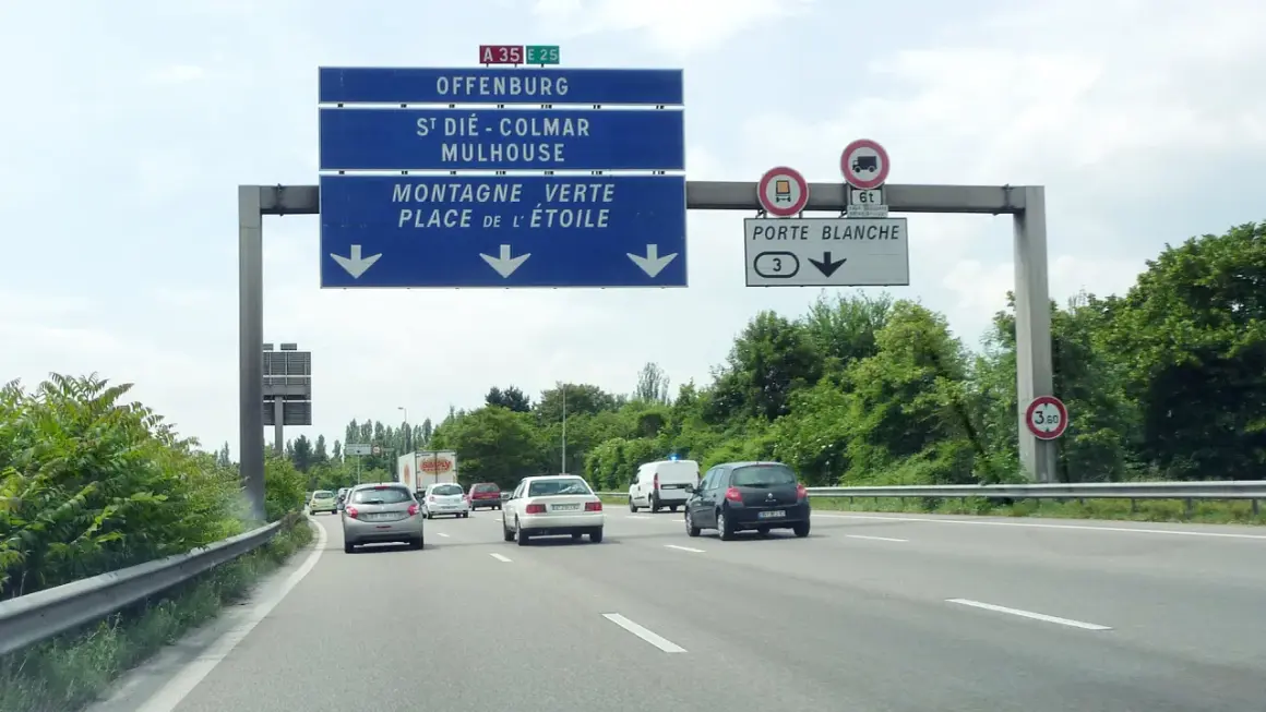 Sur l'autoroute A35, des panneaux indiquent Offenburg, Mulhouse et la Porte Blanche. Des voitures circulent par une journée nuageuse.