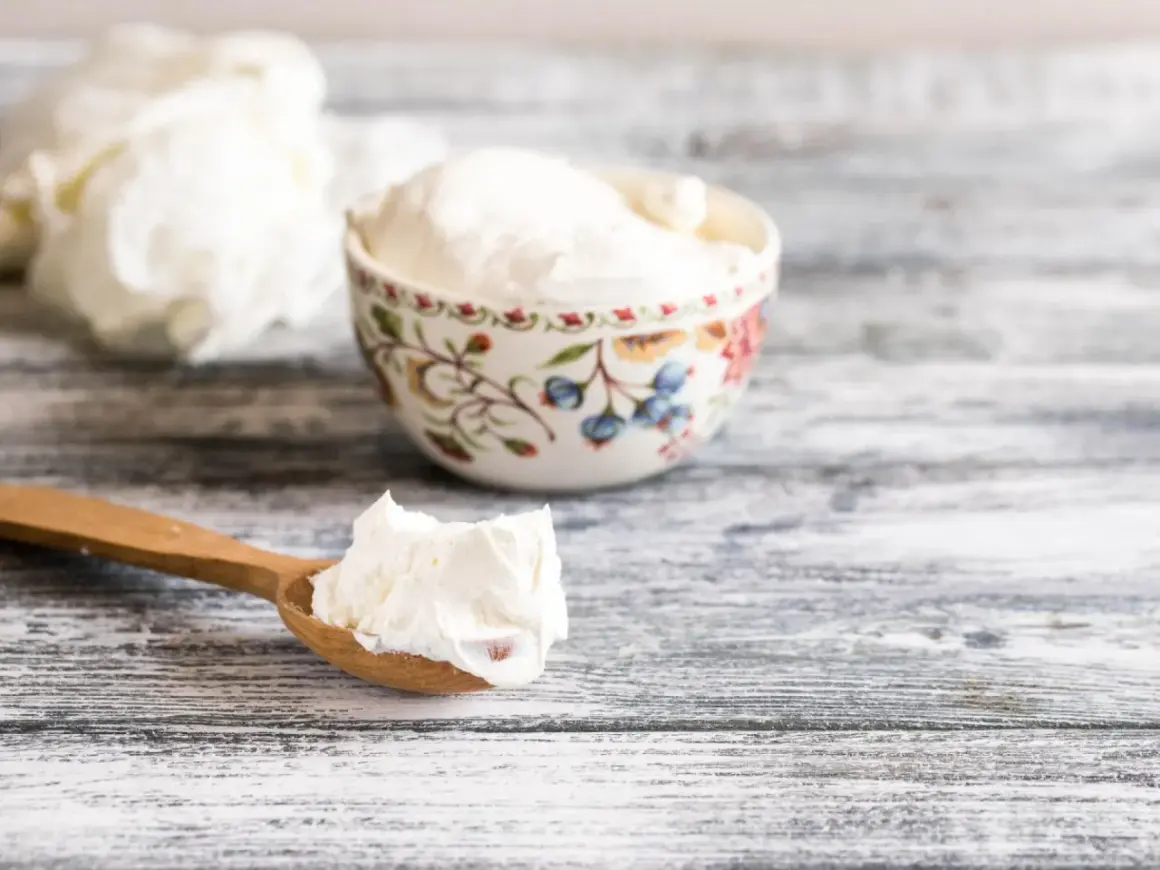 Ein Holzlöffel mit cremigem Quark, daneben eine Schale. Die Frage "wieviel Quark am Tag" beschäftigt viele.