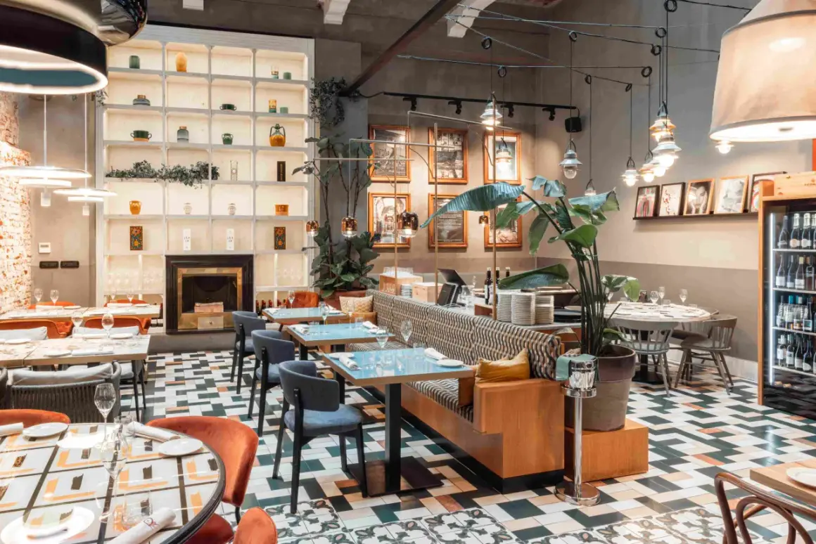 Interni eleganti di locali trendy a Milano, con tavoli apparecchiati, sedute comode e un camino decorativo.