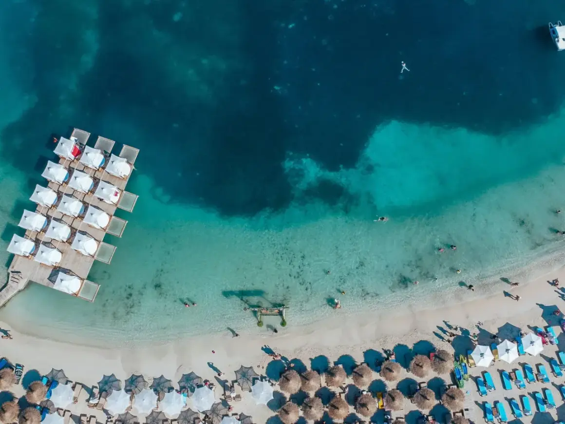 En strand med turkost vatten och solstolar, som påminner om Europas Maldiverna i Albanien.