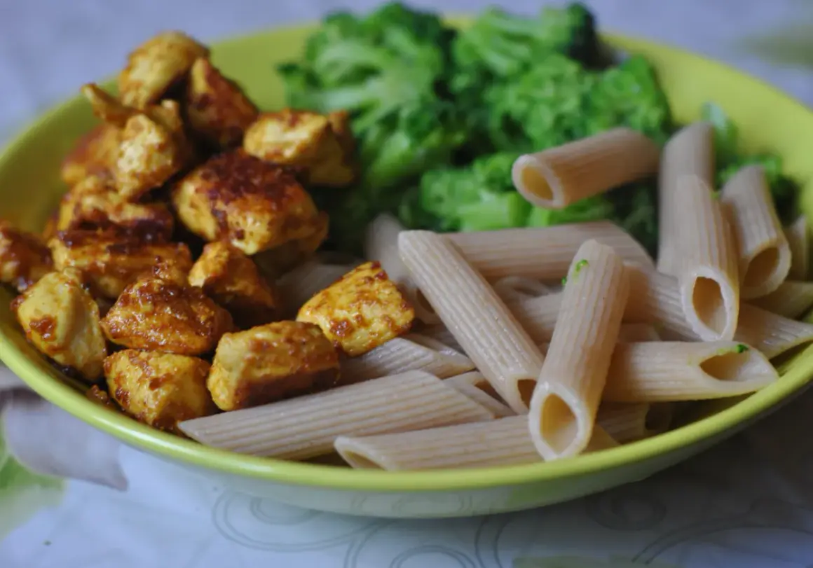 Szybkie przepisy na dania w 15 minut: kurczak w przyprawach, makaron penne i brokuły na talerzu.