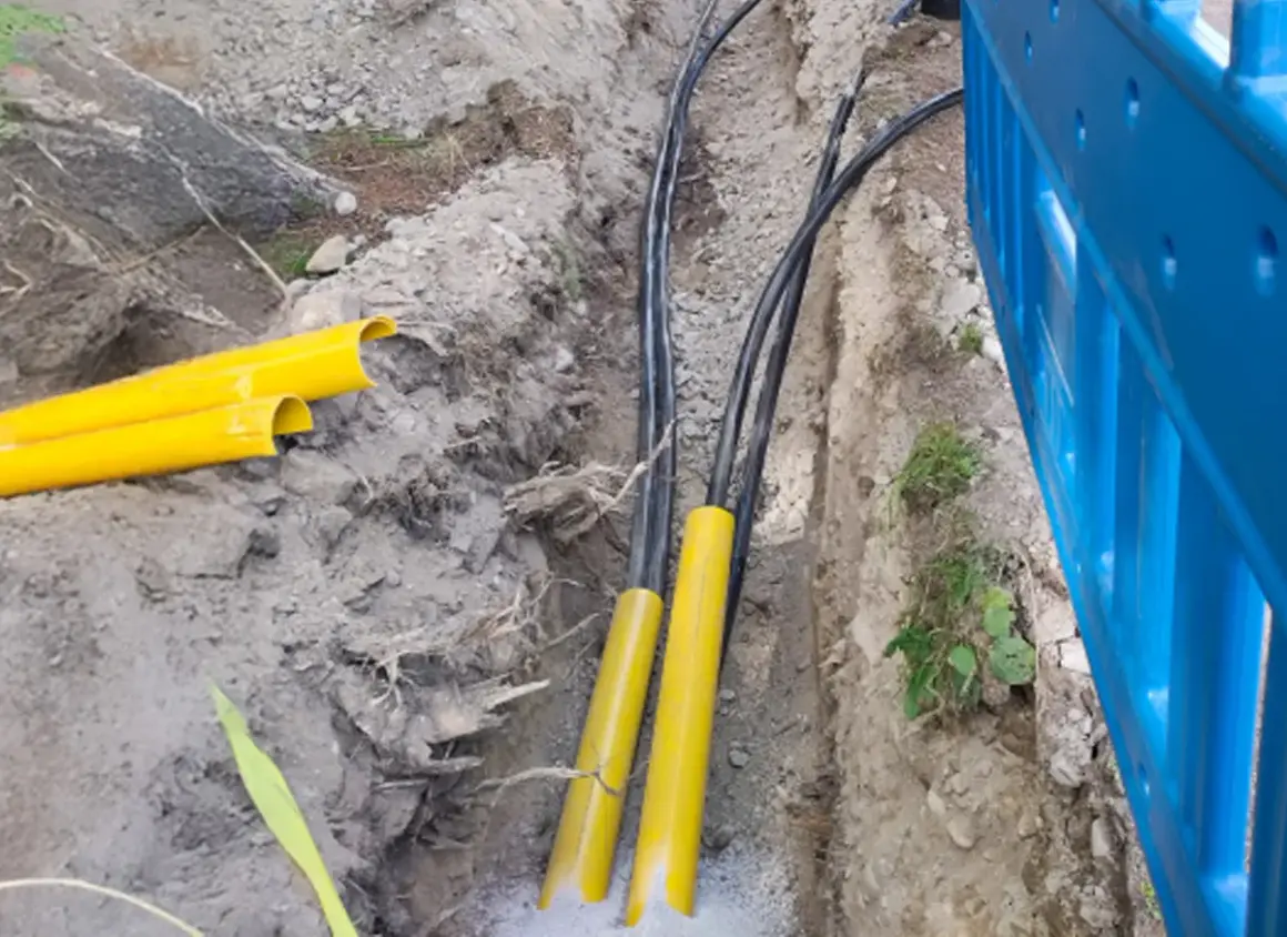 Kabel elektryczny w ziemi, chroniony żółtymi osłonami, przygotowany do zakopania zgodnie z przepisami.